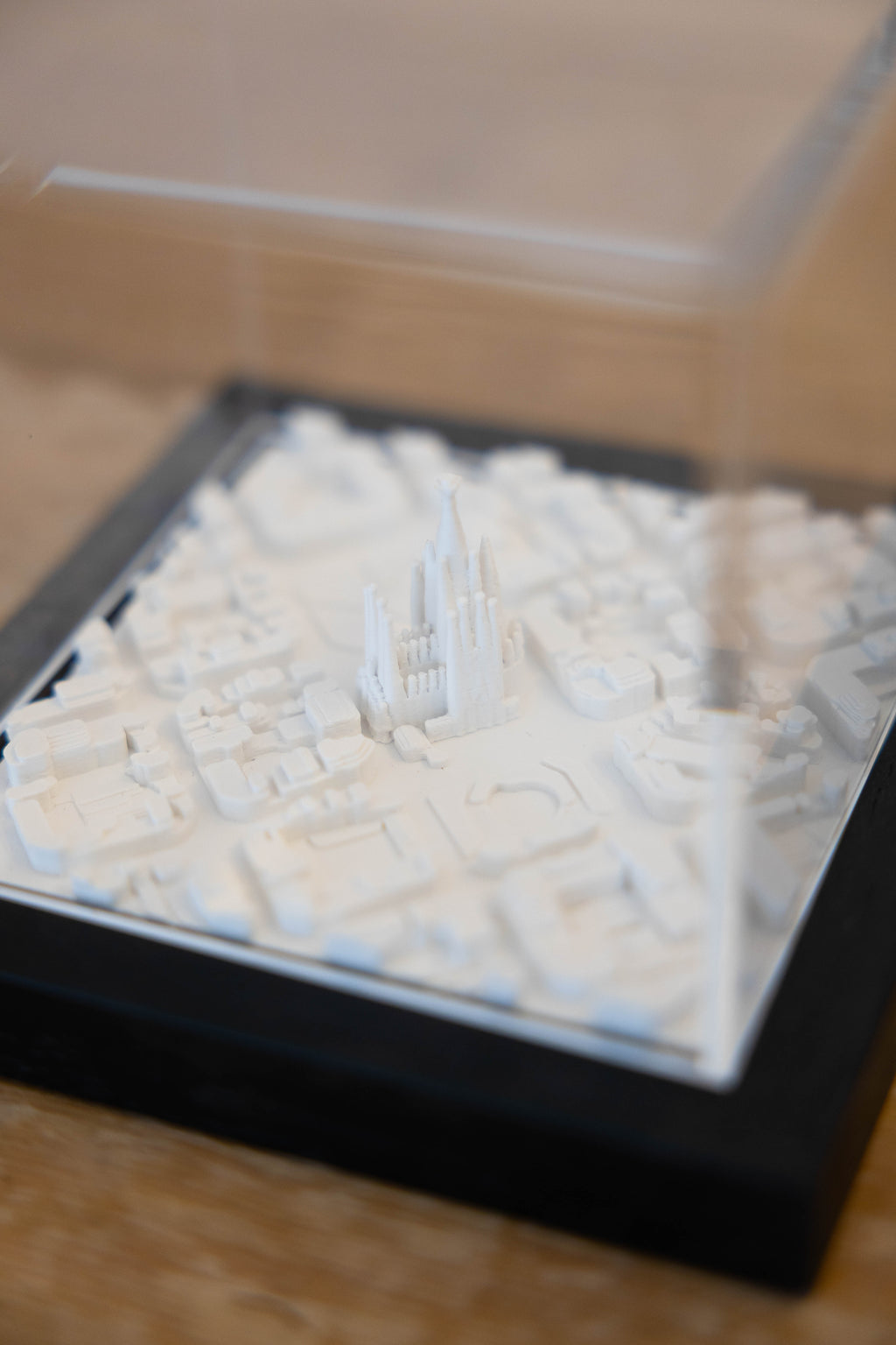 White 3D art city frame by Object and Story, featuring miniature buildings and a dark frame.