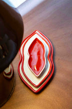 Set of three red and white heart-shaped nesting dishes on a light brown wooden surface.