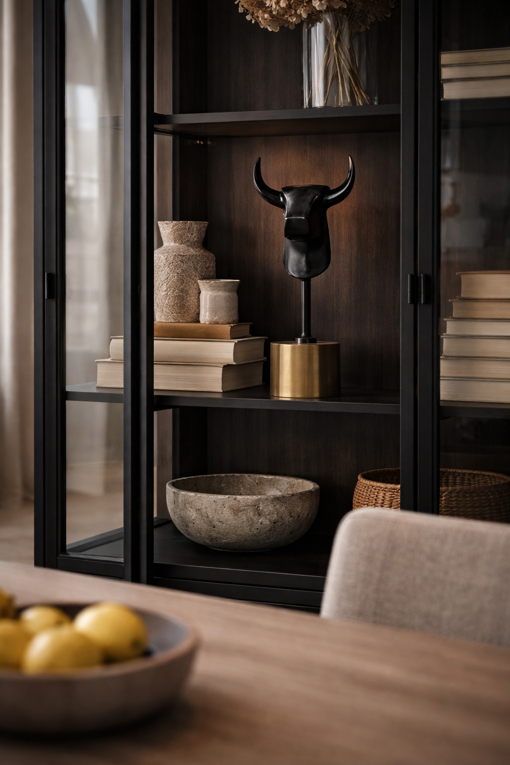 Black bull statue on a brass-colored cylindrical base, styled on a dark wooden shelf.