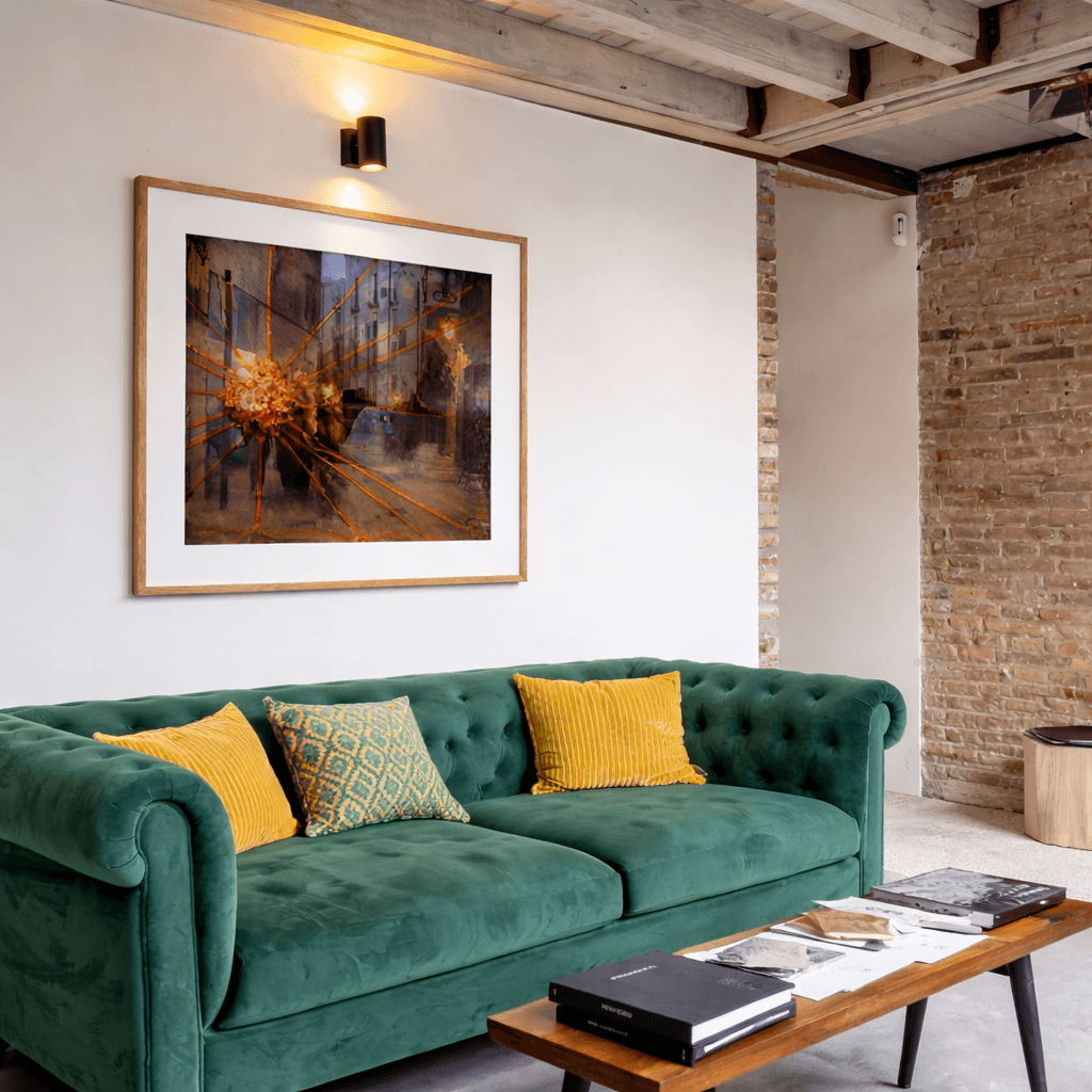 A large framed painting by Manuel Cohen depicting a dark street scene with radiating golden lines, hung above a green couch.