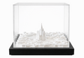 White cityscape art by Object and Story, featuring architectural models inside a transparent display case with a black base.