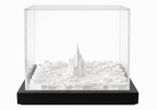 White cityscape art by Object and Story, featuring architectural models inside a transparent display case with a black base.