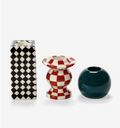A set of three patterned candle holders from Les Objets Mouleversants: rectangular black/white checkered, hourglass red/white checkered, and spherical dark green.