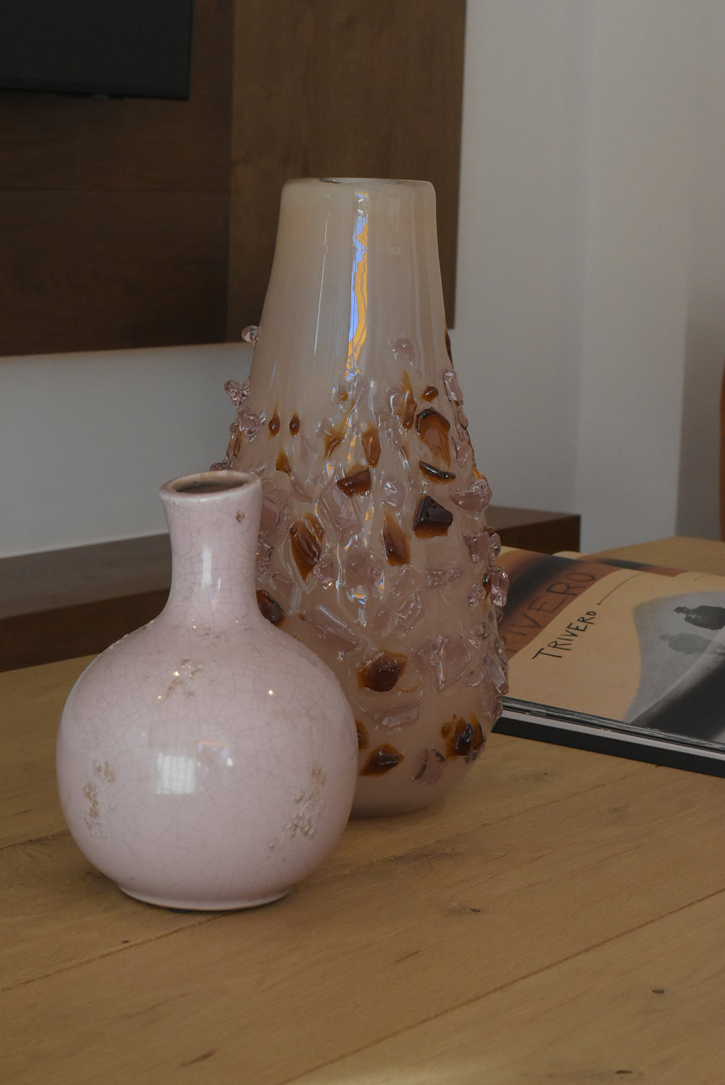 Pink quartz vase by Object and Story with a cracked texture, placed next to a patterned glass vase.
