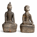 Two seated, painted earthenware sculptures depicting human figures; one with spiky hair, the other with button details.