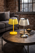 Two table lamps, one bright yellow and one silver, with ribbed conical shades on a dark coffee table.