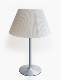 White pleated table lamp with a silver metallic stem and round base.