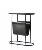 Black metal side table with an oval dark marble top and a black leather magazine holder featuring decorative stitching.