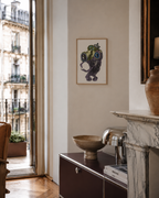 Whimsical framed artwork above modern cabinet in Parisian apartment with marble fireplace and vintage decor