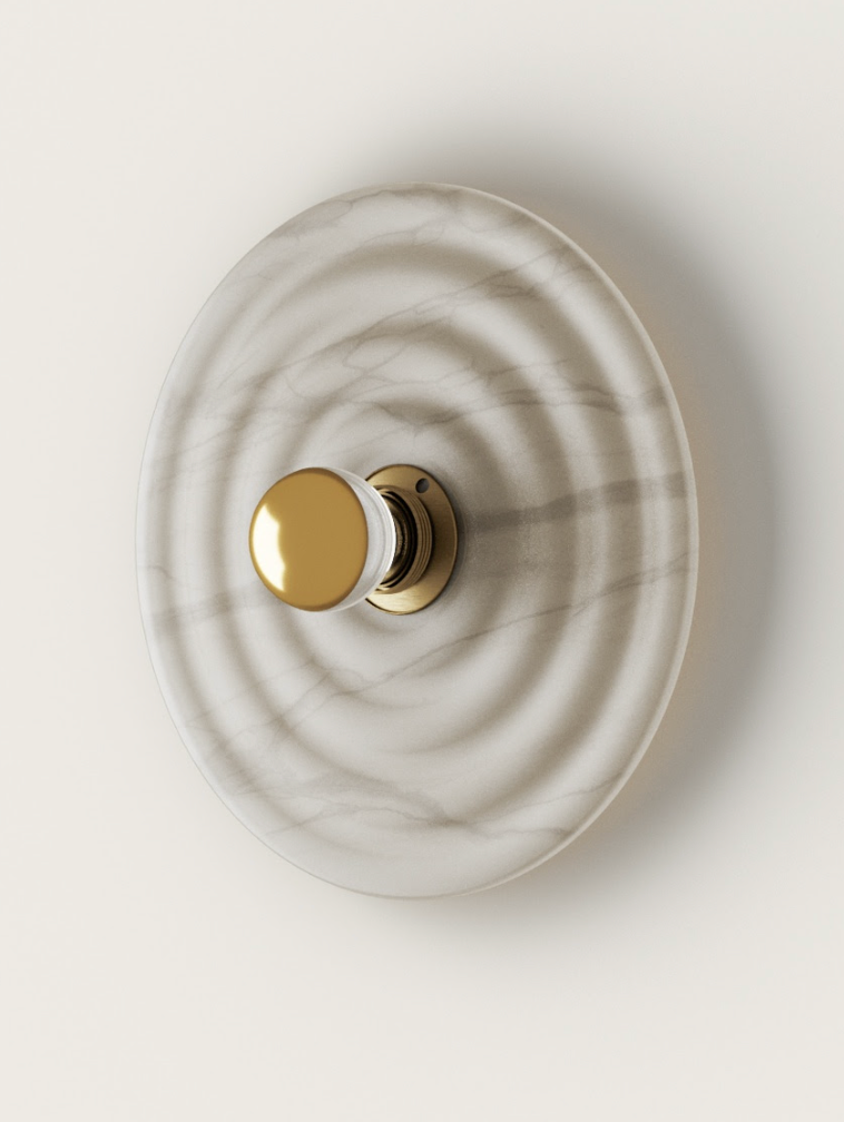 Top-down white marble wall lamp with concentric waves, featuring a gold and clear glass knob on a brass base.