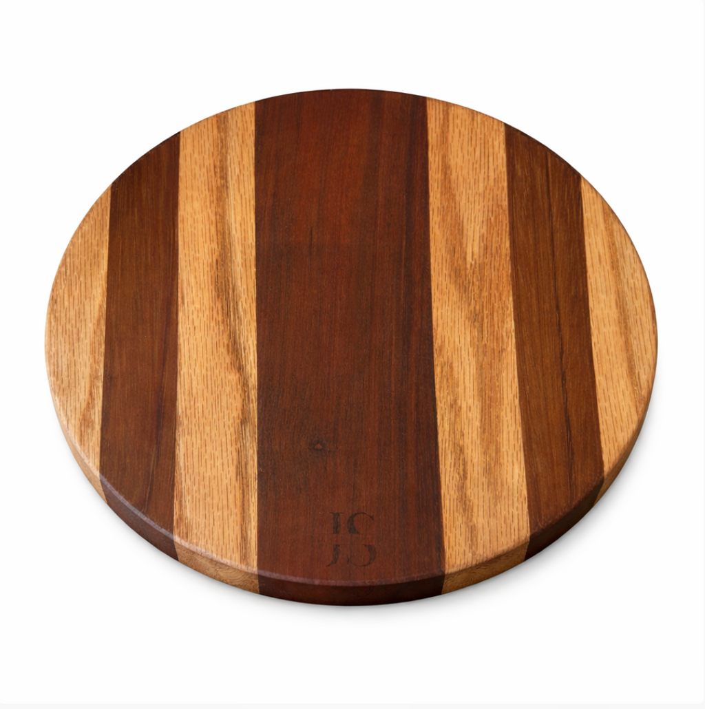 Round wood board by JS with alternating dark and light brown vertical strips, embossed with 'JS' monogram.