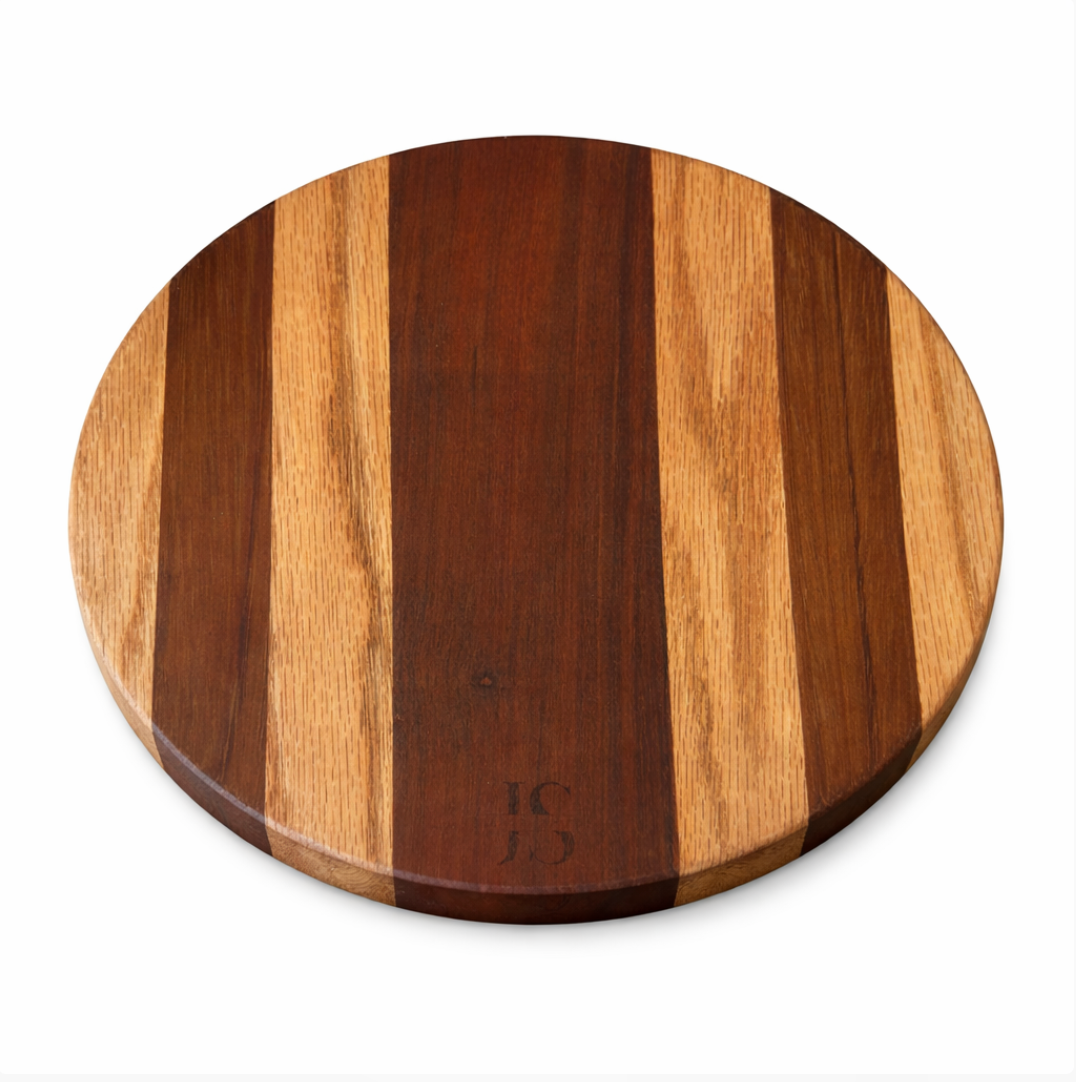 Round wood board by JS with alternating dark and light brown vertical strips, embossed with 'JS' monogram.