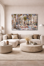 Vibrant abstract painting of a Barcelona street scene with buildings, a palm tree, and bicycles, hung above a cream sofa.