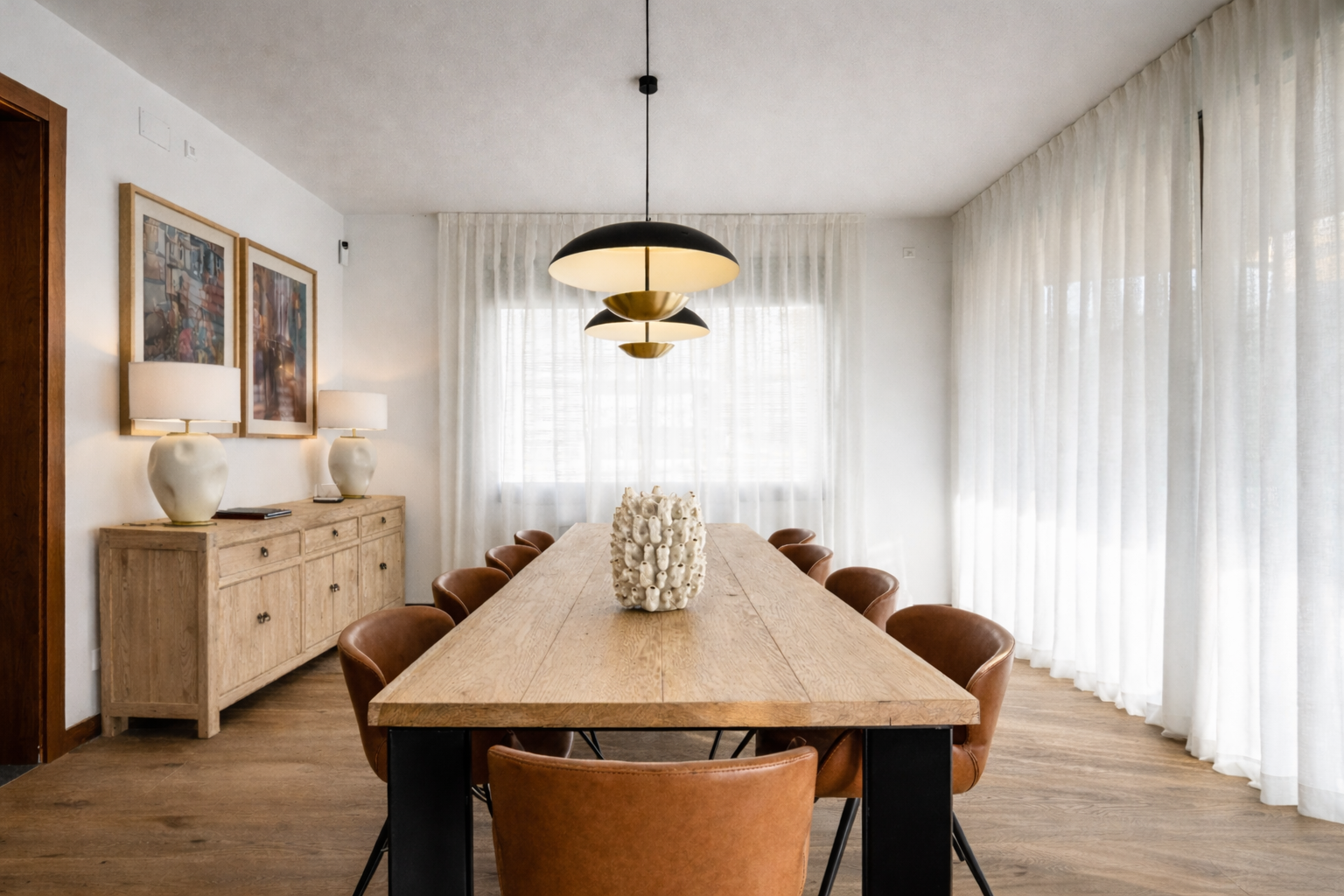 White patterned vase by Object and Story centered on a wooden dining table in a bright dining room.
