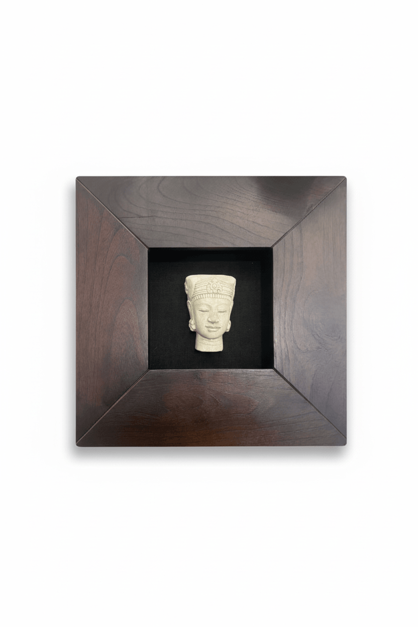 Zen Buda image carved in off-white material, displayed in a dark wood shadow box frame against a black background.