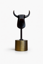 Minimalist dark bronze bull statue standing upright on a cylindrical gold base.