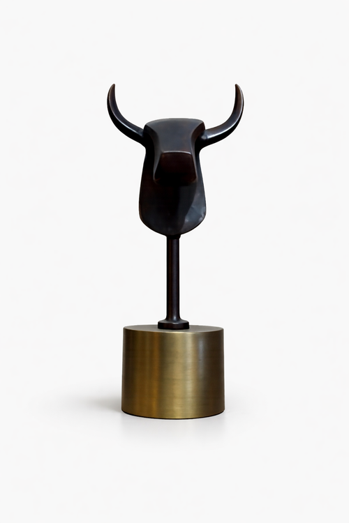 Minimalist dark bronze bull statue standing upright on a cylindrical gold base.