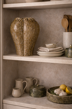 Textured brown ceramic vase with a sculptural form and ruffled rim, displayed on a kitchen shelf.