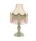 Table lamp with a sage green base and scalloped fabric shade featuring cream, sage green, and light brown fringes.
