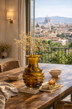 A ribbed honey amber glass vase with a wavy rim, filled with dried flowers on a rustic wooden table.