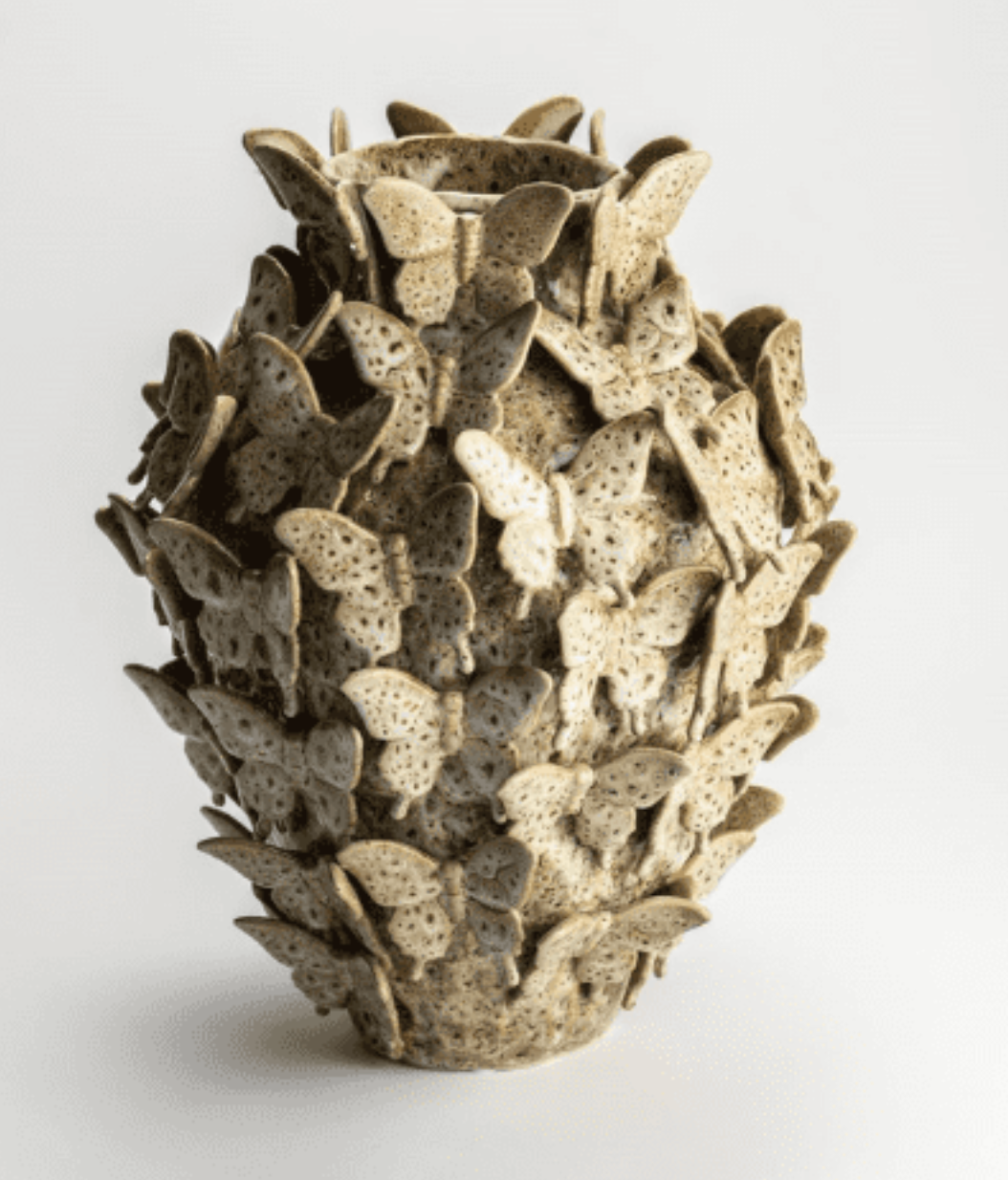 Light brown ceramic vase by Isaa Colares, heavily textured with numerous small butterflies.