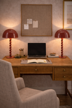 Coral red table lamp by Luox featuring a twisted base and dome shade, placed on a wooden desk.