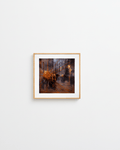 Framed abstract painting by Manuel Cohen, a dark street scene with radiating orange lines in warm tones, on a white wall.