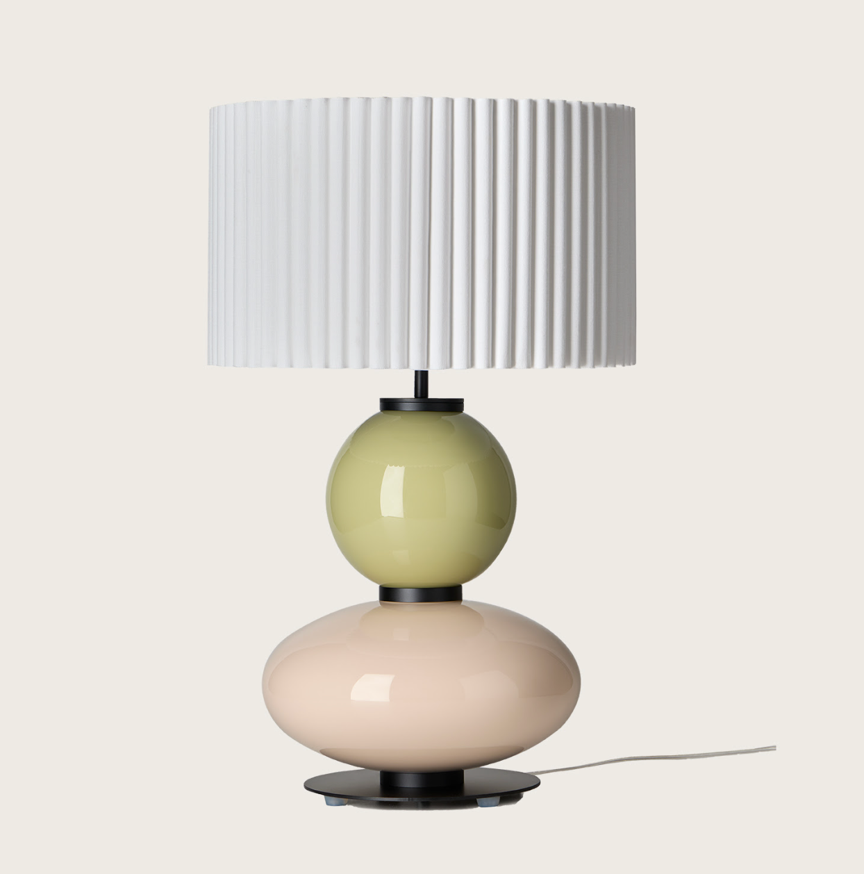White pleated table lamp with stacked pale green and pink glossy spherical bases.