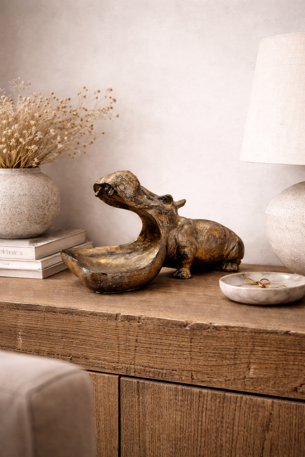 Bronze hippo-shaped Muth Decorative Bowl with an open mouth, on a wooden cabinet.