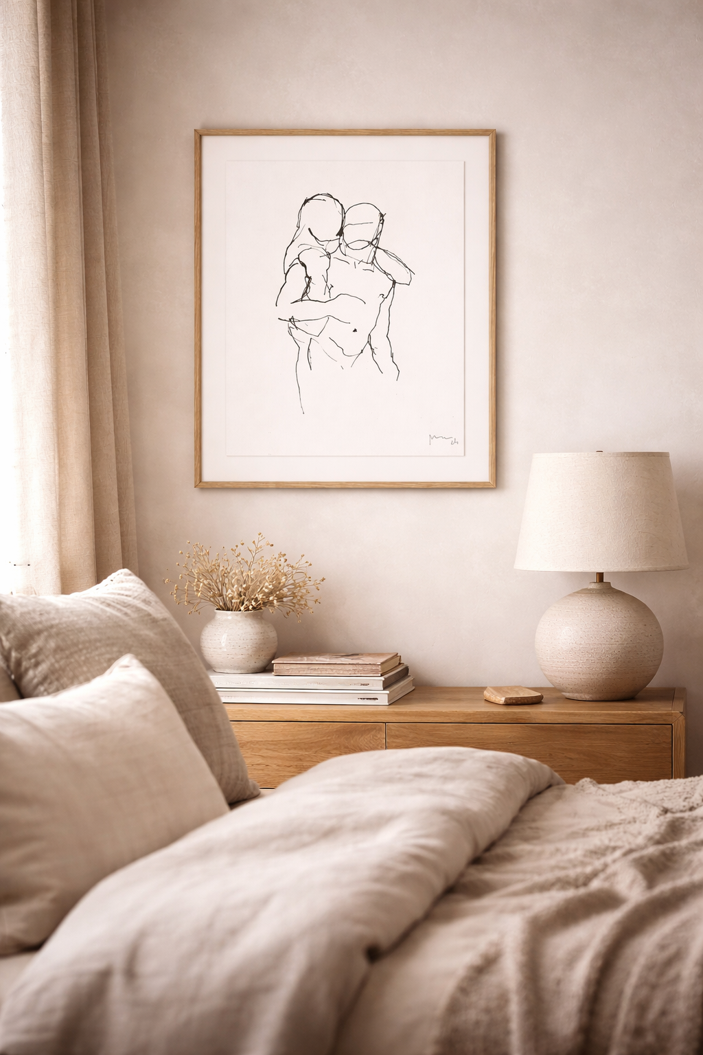 Framed minimalist line art painting of two embracing figures, hanging above a wooden dresser in a neutral bedroom.