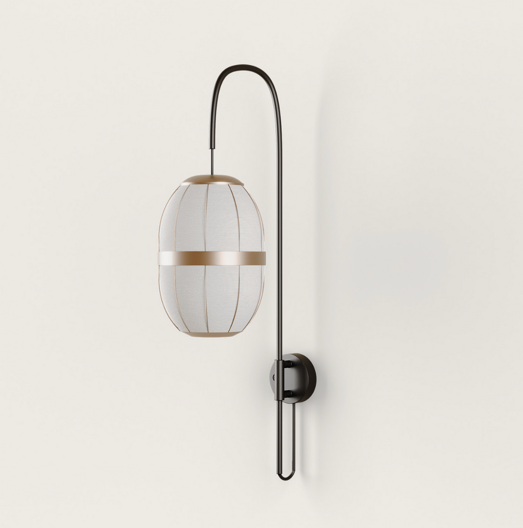 Dark metal wall lamp with an elongated light fabric shade and golden accent band, mounted on a cream wall.