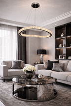 Oval crystal ring chandelier lamp with a black and silver frame suspended in a modern living room.