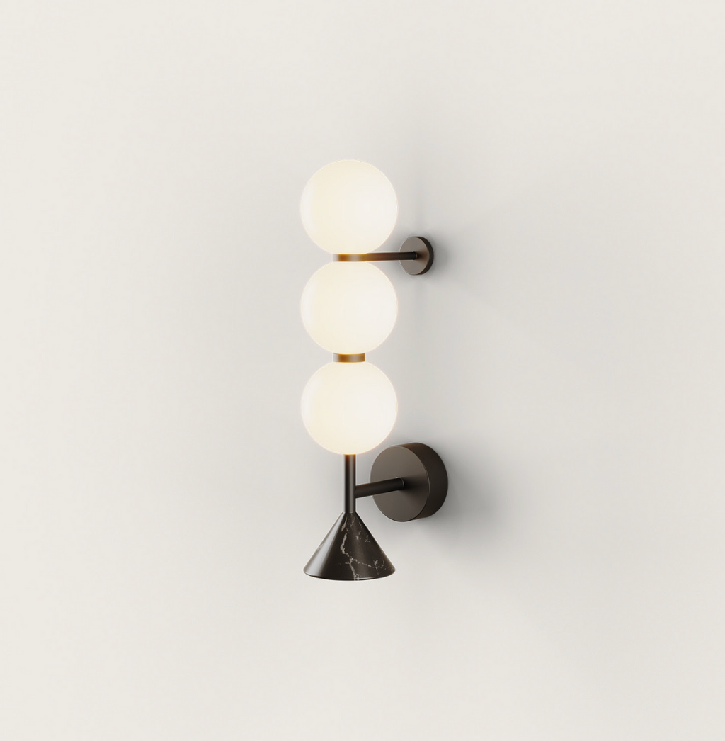 Dark metal wall lamp with three glowing white spherical globes and a black marble conical base, mounted vertically.