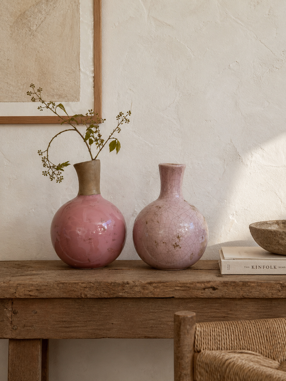 Two Ubrik pink ceramic vases, one glossy and one with crackle glaze, on a rustic wooden table.