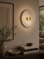 Round waves wall lamp with a translucent marble-like ripple pattern and a central brass knob, emitting a warm glow.
