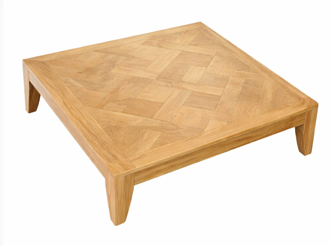 Square light brown wood coffee table with a parquet top and sturdy block legs.