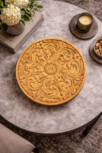 Round Nordic wood tray with an intricate floral carving, styled on a modern grey table with decorative items.